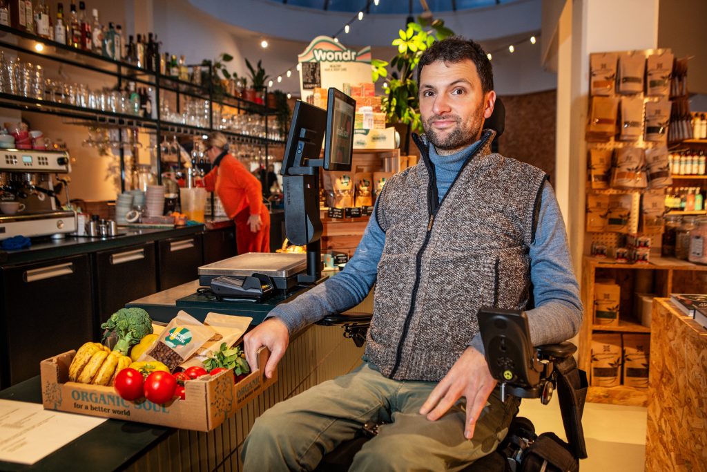 Rolstoelgebruiker Cor Van Damme bij verlaagde toonbank in Knok&Kool