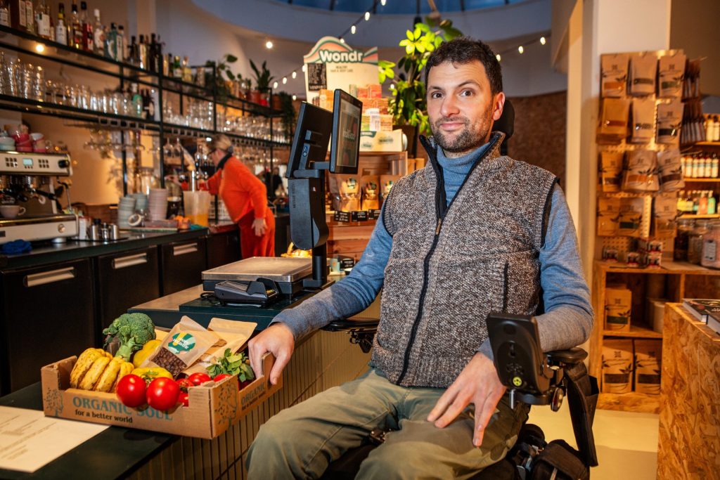 Rolstoelgebruiker Cor Van Damme bij verlaagde toonbank in Knok&Kool